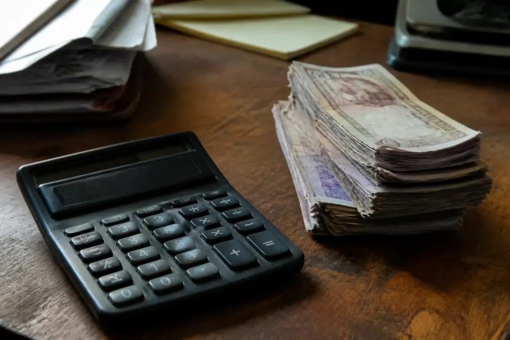 Calculatrice et pile de billets sur bureau en bois