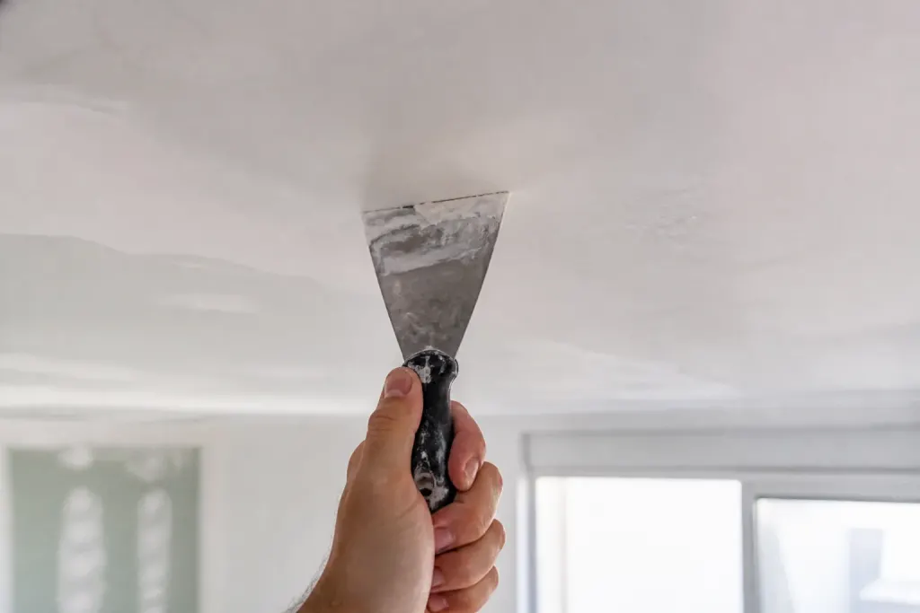 Main tenant une spatule contre un plafond blanc