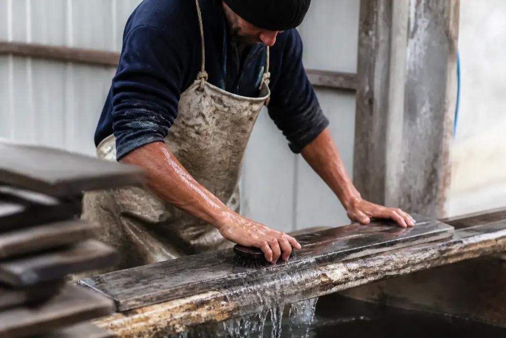 Ouvrier brosse planche de bois grise sous eau