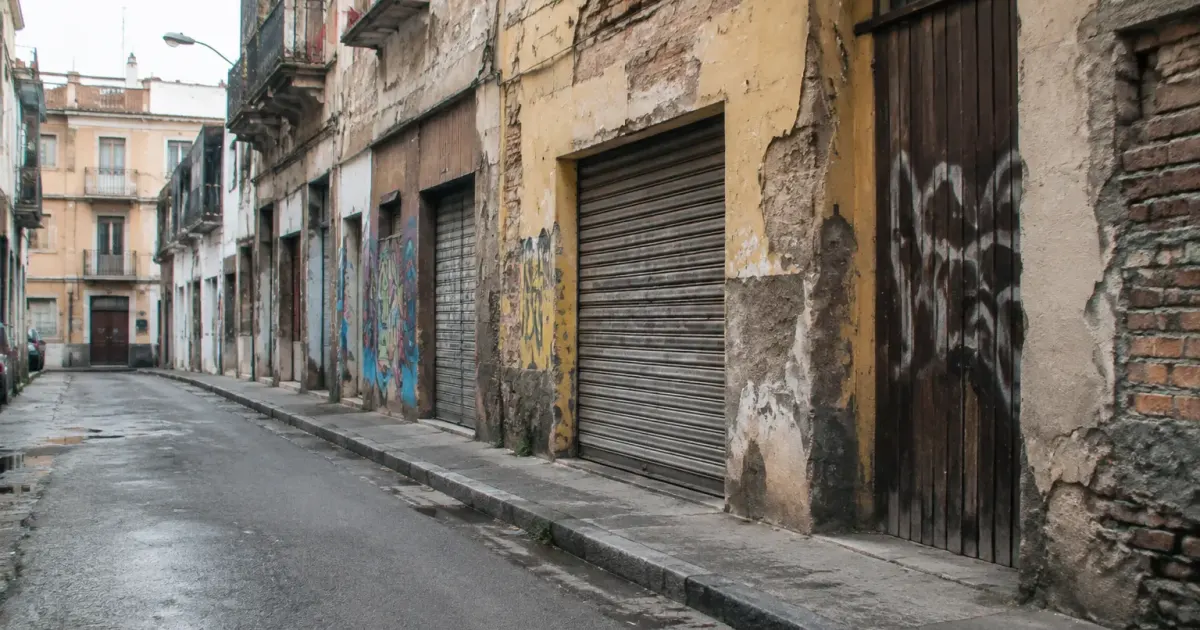 Rue urbaine delabree avec facades graffitees et portes fermees